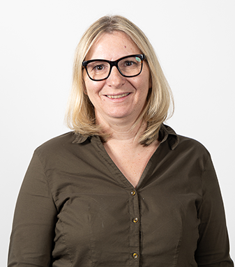 Das Foto zeigt Petra Neuherz-Steindl, unsere Bereichsleiterin Arbeiten. Sie hat eine schwarze Brille, blonde mittlere Haare, lächelt in die Kamera und trägt eine braune Bluse.