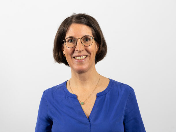 Die Mitarbeiterin Maria Hoerlesberger schaut freundlich in die Kamera. Sie die Leiterin des Bereichs Teilbetreutes Wohnen in der Lebenshilfe Wien. Sie hat einen braunen Pagenkopf, eine Brille und trägt eine blaue Bluse auf dem Foto.