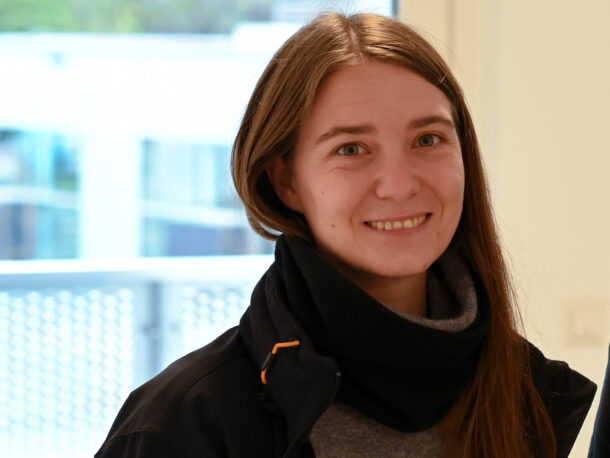 Die Bereichsleitung Wohnen Cornelia Baumgartner hat lange braune Haare, ein freundliches Laecheln. Sie hat einen Schal um den Hals und traegt eine schwarze Jacke.