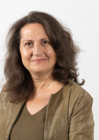 Die Mitarbeiterin Mag.a Ingrid Wick schaut freundlich in die Kamera. Sie verantwortet die Sozialarbeit und das Platzmanagement in der Lebenshilfe Wien. Sie hat lange dunkle Haare und trägt eine olivfarbene Jacke.