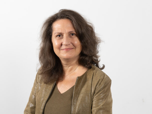 Die Mitarbeiterin Mag.a Ingrid Wick schaut freundlich in die Kamera. Sie verantwortet die Sozialarbeit und das Platzmanagement in der Lebenshilfe Wien. Sie hat lange dunkle Haare und trägt eine olivfarbene Jacke.