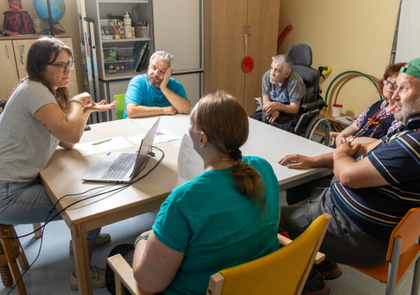 Eine sechsköpfige Personengruppe sitzt am Tisch und diskutiert.