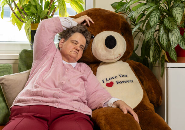 Eine blinde, ältere Frau kuschelt sich an einen großen Teddybären.