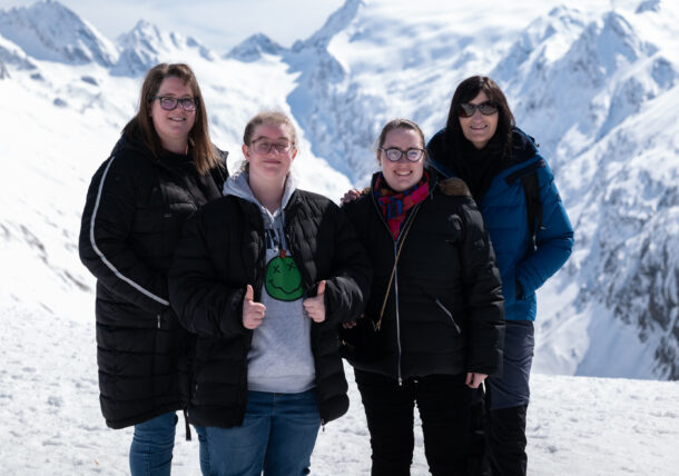 Vier Frauen posieren vor einem Bergpanrama im Schnee