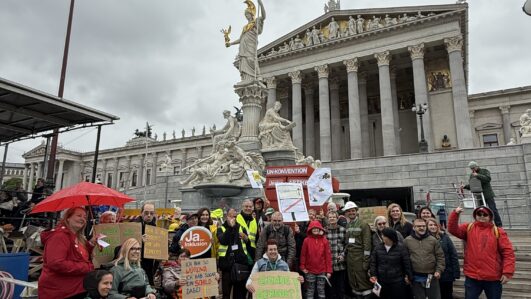 Eine Gruppe von Menschen mit und ohne Behinderungen protestiert vor dem Parlament in Wien. Die Aktion heißt BAUSTELLE INKLUSION