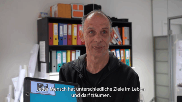 Ein Kunde der Lebenshilfe Wien hält sein Tablet in die Kamera
