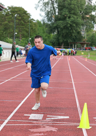 Ein Mann mit blauem Sportgewand läuft auf einer Laufbahn